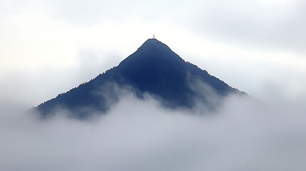 Misty mountain peak emerging from clouds.