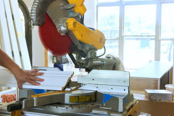 Trim worker operates miter saw, cutting molding with precision in home renovation interior