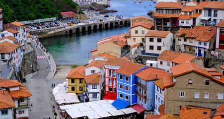 A picturesque view of a charming coastal village nestled into a hillside, with colorful traditional houses cascading down towards a tranquil harbor. Cudillero, Spain