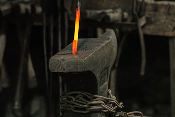 A red-hot iron rod being bent on an anvil in a blacksmith's shop