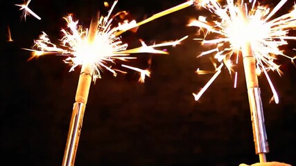 Close-Up Shot of Brightly Lit Sparklers Emitting Glowing Sparks Against Dark Black Background