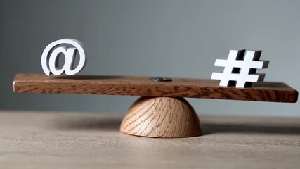 White at symbol and black hashtag balanced on wooden seesaw scale - Powered by Adobe