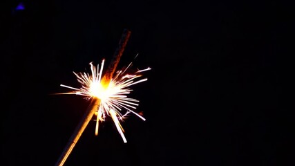 Close-Up Shot of Brightly Lit Sparklers Emitting Glowing Sparks Against Dark Black Background