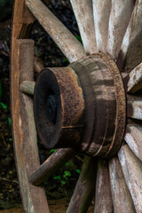 An old wooden wagon wheel mounted on a horse-drawn wagon in a barn