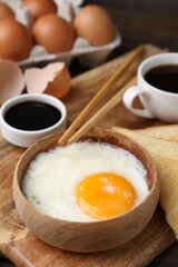 Half-boiled egg in bowl, soy sauce, chopsticks, coffee and toasted bread on table, closeup. Traditional asian breakfast