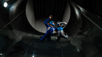 A male instructor teaches a woman how to fly in a wind tunnel. Free fall simulator.