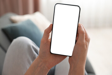 Woman using modern smartphone on sofa at home, closeup