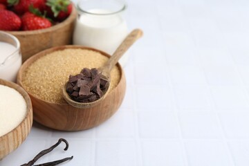 Different ingredients for panna cotta. Milk, sugar, vanilla, chocolate and strawberries on white tiled table, closeup. Space for text
