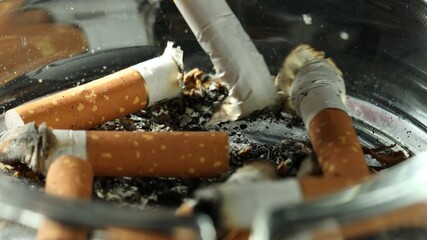 Cigarette butts in ashtray on black background, closeup