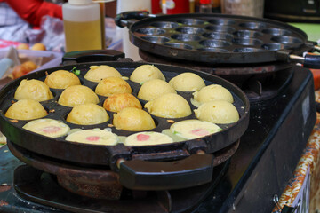 Food seller making takoyaki, a delicious street food at pringgondani market. Processed to cooking the populer fried ballswith octopus.