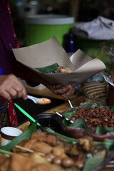 Pecel rice seller is preparing buyer orders at the traditional market. Nasi pecel is an Indonesian rice dish from Java served with pecel (cooked vegetables and peanut sauce)