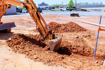 Heavy machinery works to dig trench into ground at construction site