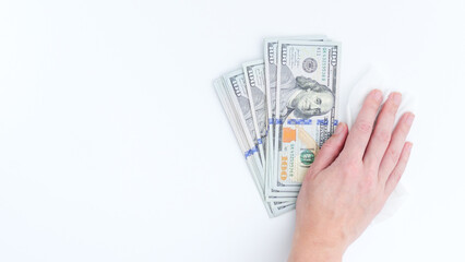 Hand is cleaning stack of hundred dollar bills on white surface, showcasing the importance of...