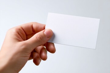 Obraz premium A hand holds a blank white business card against a neutral backdrop