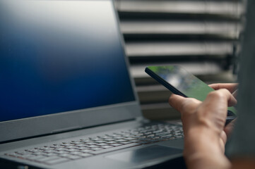 Person Using Smartphone While Working on Laptop in Modern Office