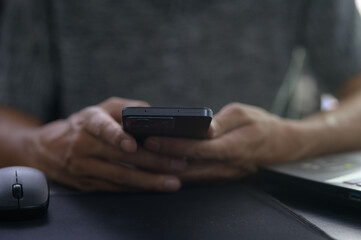 Person Holding Smartphone While Working at Desk with Laptop Mouse
