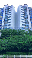 Two tall apartment buildings stand side by side in perfect symmetry, rising boldly into the sky. Their modern design and mirrored alignment create a striking visual harmony, capturing the essence of u