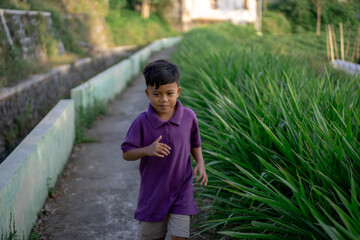 Child jogging alone in nature near the garden park on a very sunny day. High quality photo