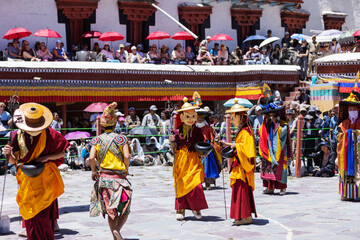 Fototapeta premium Monks in colorful costumes and masks perform a traditional dance during the Hemis Festival in Leh, Ladakh. The vibrant cultural celebration draws crowds who gather to witness this sacred ritual.
