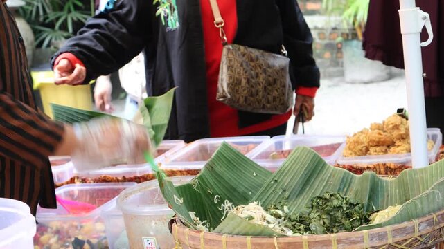 Pecel rice seller is preparing buyer orders at the traditional market. Nasi pecel is an Indonesian rice dish from Java served with pecel (cooked vegetables and peanut sauce)