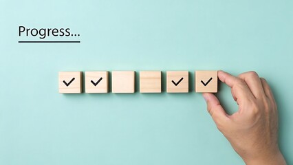 Hand placing wooden block with checkmark in progress bar on blue background checklist wooden blocks