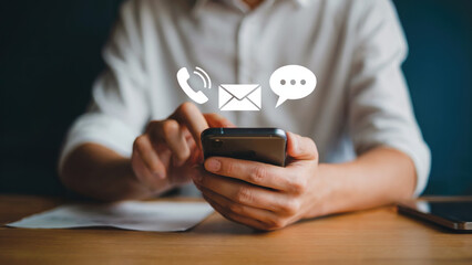 Contact icons above smart phone held by a man in white shirt