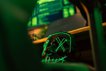 In a dimly lit cyber lair, a glowing hacker mask watches over a desk as encrypted code streams...