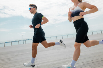 Running along the waterfront, two fitness enthusiasts embrace the sunny day