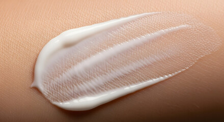 Fototapeta premium Close-up of a swirl of white cream or lotion spread on human skin, showing texture and application.