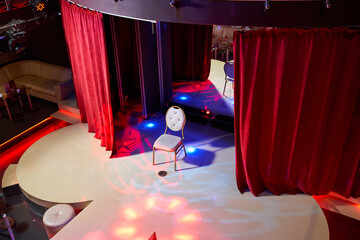 A vibrant stage with luxurious red curtains and a brilliant spotlight for captivating shows