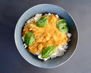 A top view of butter chicken and white rice in a bowl.
