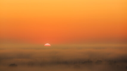 Sunrise over foggy landscape with orange sky