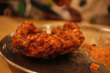 Authentic South Indian Paruppu Vadai on Traditional Steel Plate – Crispy Dal Fritter Snack with Chutney – Deep Fried Indian Street Food Close-up in Warm Ambient Light
