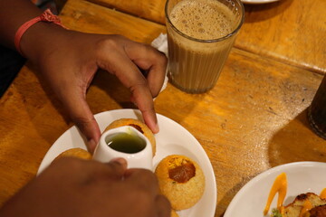Authentic Indian Street Food – Hand Preparing Spicy Pani Puri with Tangy Jaljeera Water and Masala Filling, Served with Hot Cutting Chai on Rustic Wooden Table – High Resolution Food Photography