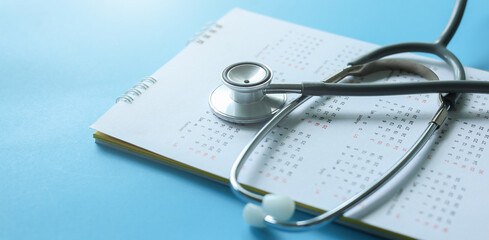 close up top view on stethoscope on calendar with over blue background for design about ads or...