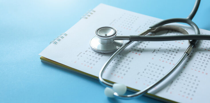 close up top view on stethoscope on calendar with over blue background for design about ads or banner of doctor appointment and health checkup following personal lifestyle concept