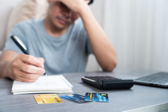 Asian man feeling stressed and worried because of unpaid bills and credit card debt, struggling with growing money problems and unsure how to handle financial pressure 