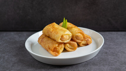 Sosis Solo (Sausage Solo). Special designation for a chicken dish wrapped in an omelet and shape like sausagea. Traditional Indonesian meat snack, served on a white plate with green chili garnish.