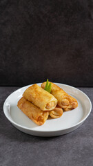 Sosis Solo (Sausage Solo). Special designation for a chicken dish wrapped in an omelet and shape like sausagea. Traditional Indonesian meat snack, served on a white plate with green chili garnish.