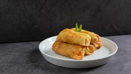 Sosis Solo (Sausage Solo). Special designation for a chicken dish wrapped in an omelet and shape like sausagea. Traditional Indonesian meat snack, served on a white plate with green chili garnish.