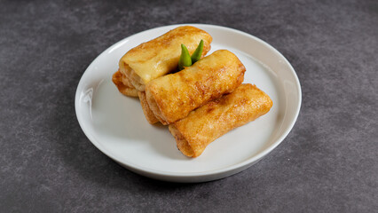 Sosis Solo (Sausage Solo). Special designation for a chicken dish wrapped in an omelet and shape like sausagea. Traditional Indonesian meat snack, served on a white plate with green chili garnish.