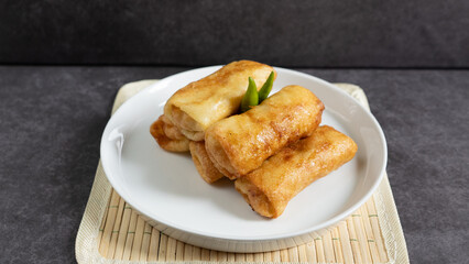 Sosis Solo (Sausage Solo). Special designation for a chicken dish wrapped in an omelet and shape like sausagea. Traditional Indonesian meat snack, served on a white plate with green chili garnish.