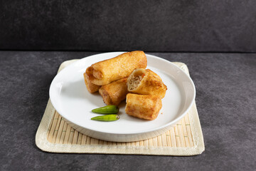 Sosis Solo (Sausage Solo). Special designation for a chicken dish wrapped in an omelet and shape like sausagea. Traditional Indonesian meat snack, served on a white plate with green chili garnish.