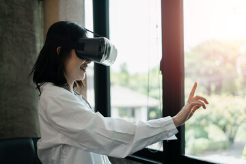 Woman using VR headset, interacting with virtual environment in a sunlit room.