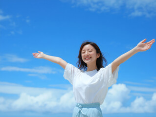 青空の下で両手を広げて笑顔を見せる日本人女性
