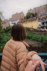 Woman leading man to the dean village in edinburgh. Woman in down jacket clothes leading man to the dean village in edinburgh, Scotland. Traveling together. Follow me.