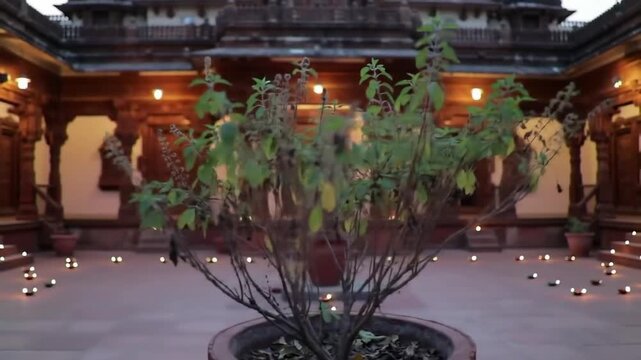 Traditional Gujarati haveli with intricate wood carvings, courtyard with tulsi plant, diya lamps glowing at dusk"