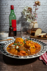 Delicious beef stew called carbonada with vegetables, corn, and wine enjoyed at rustic table setting