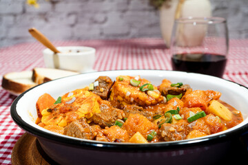 Delicious beef stew called carbonada with potatoes, corn, and carrots simmering in a rustic bowl