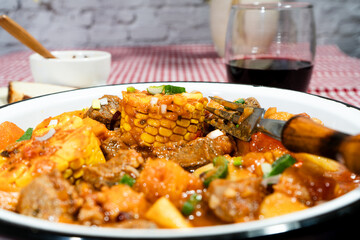 Delicious beef stew called carbonada with corn, potatoes, and carrots simmering in rich tomato sauce